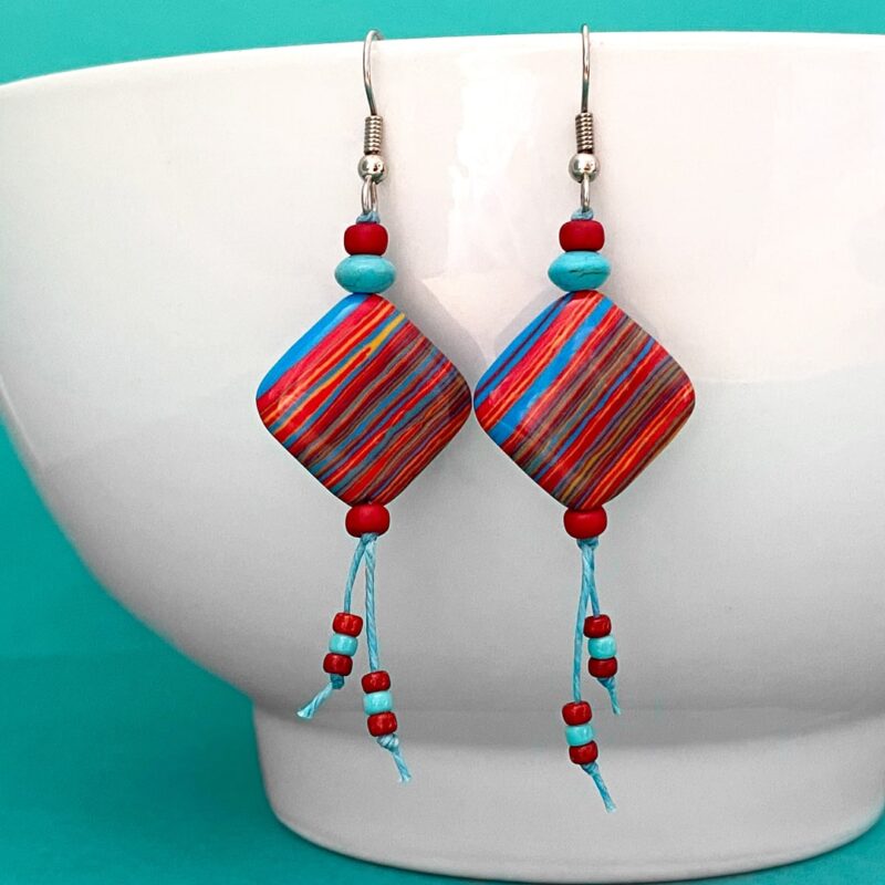 Red, blue and yelllow striped earrings on turquoise waxed cord.