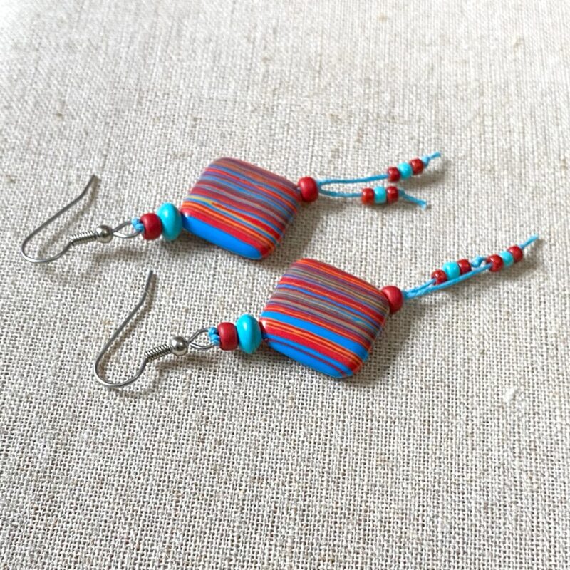 Red, blue and yelllow striped earrings on turquoise waxed cord.