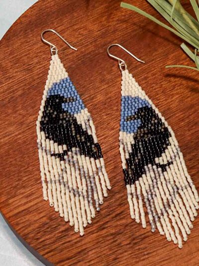 Beaded fringe earrings. Cream background with blue moon and black raven.
