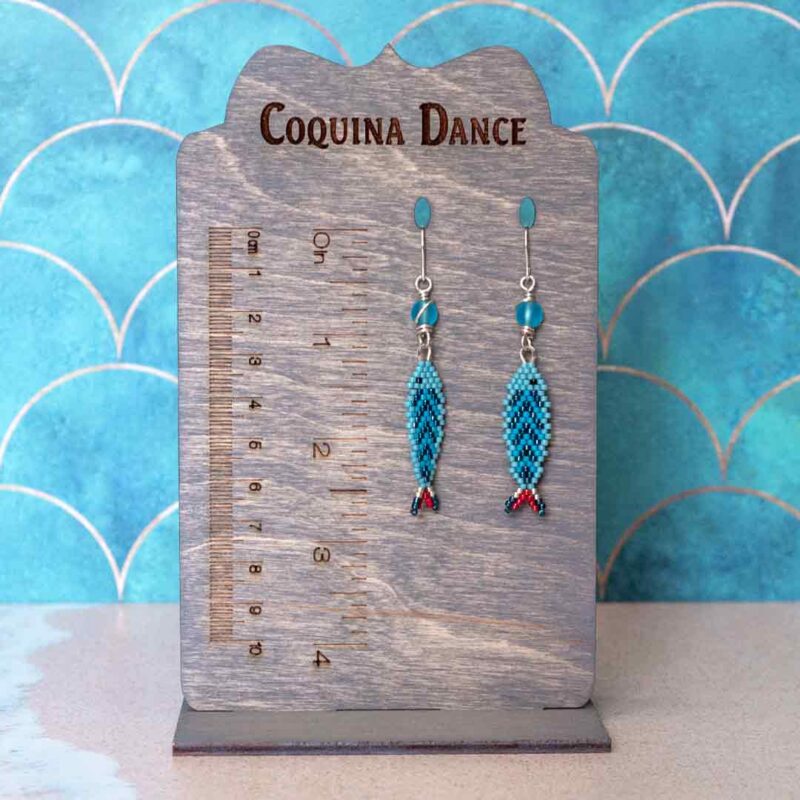 1 pair of stitched fish earrings on a measurement stand