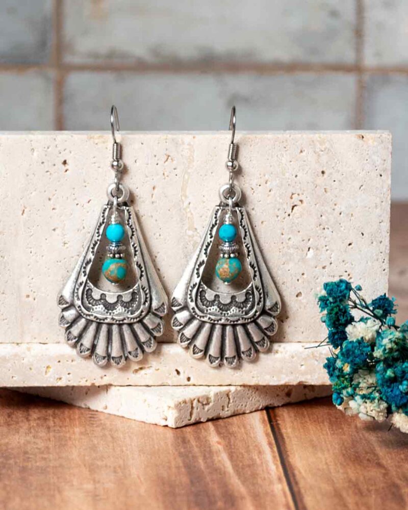 Earrings displayed on stone slabs.