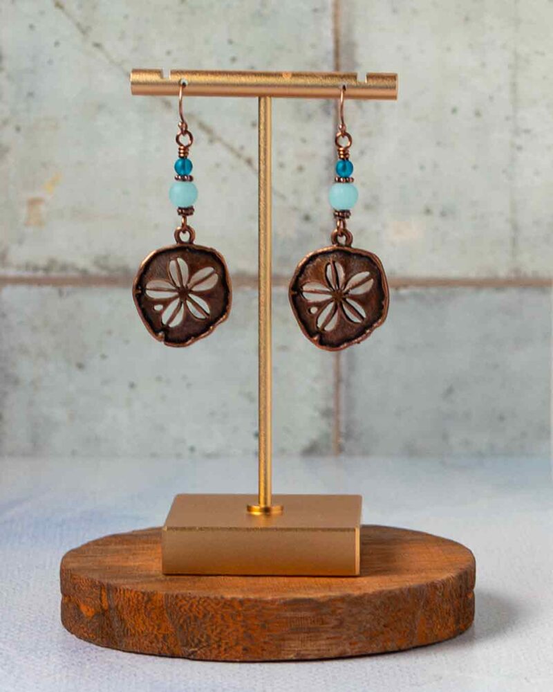 Copper Sand Dollar Earrings hanging on stand