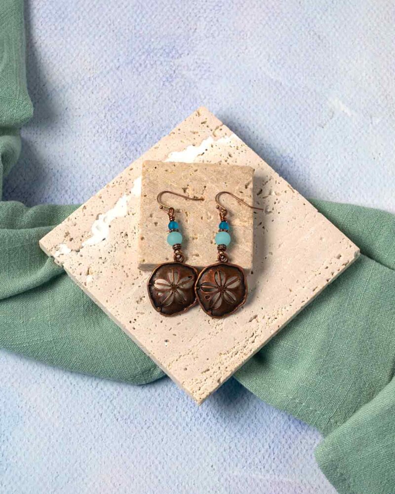 Copper Sand Dollar Earrings on stone slabs