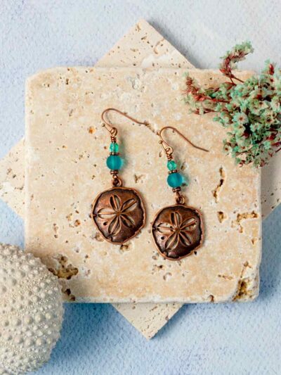 Copper Sand Dollar Earrings on stone slabs